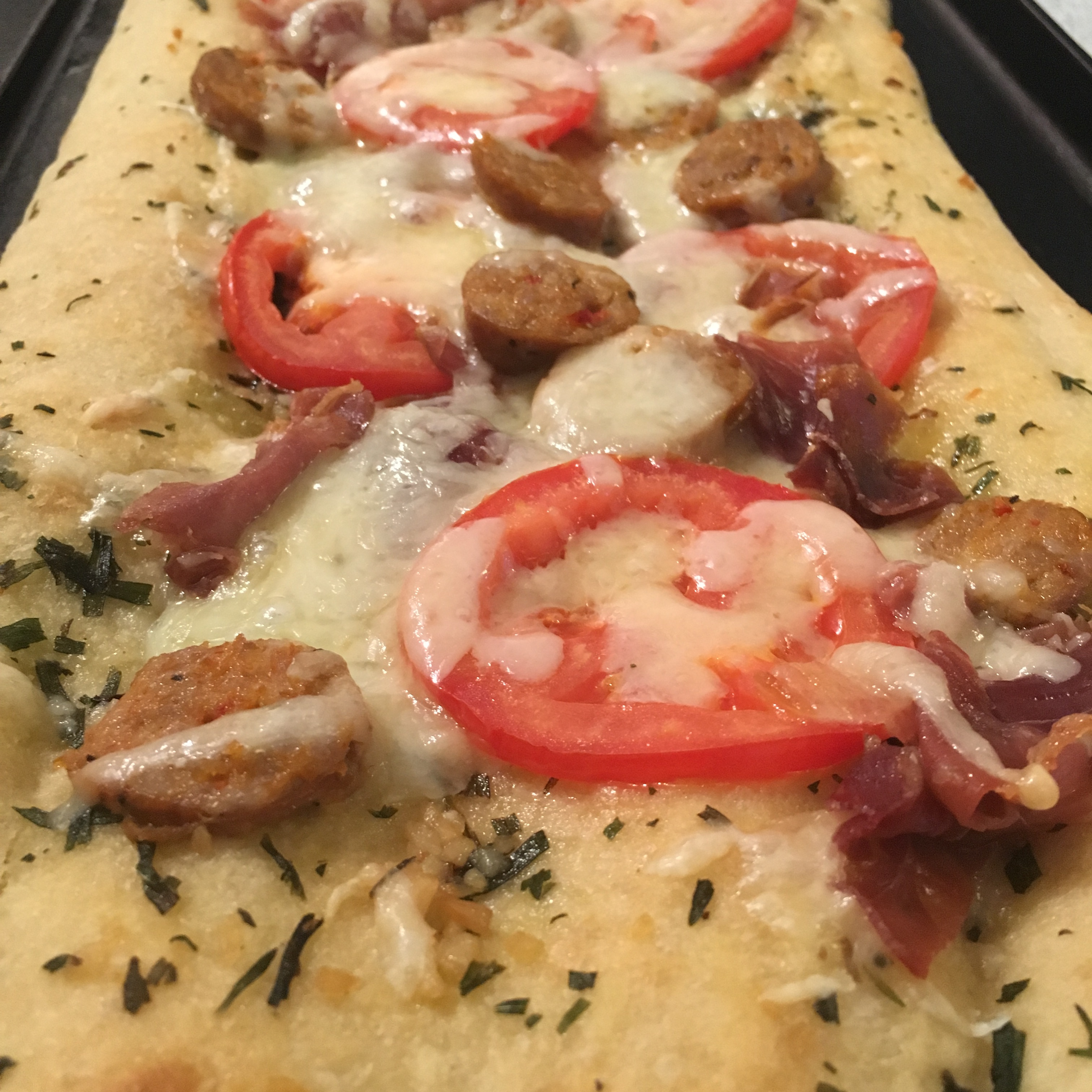 Fokachio Flat Bread Pizza with tomato, basil, garlic, prosciutto, Italian sausage, mozzarella and olive oil